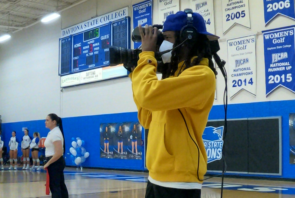 student filming a volleyball game