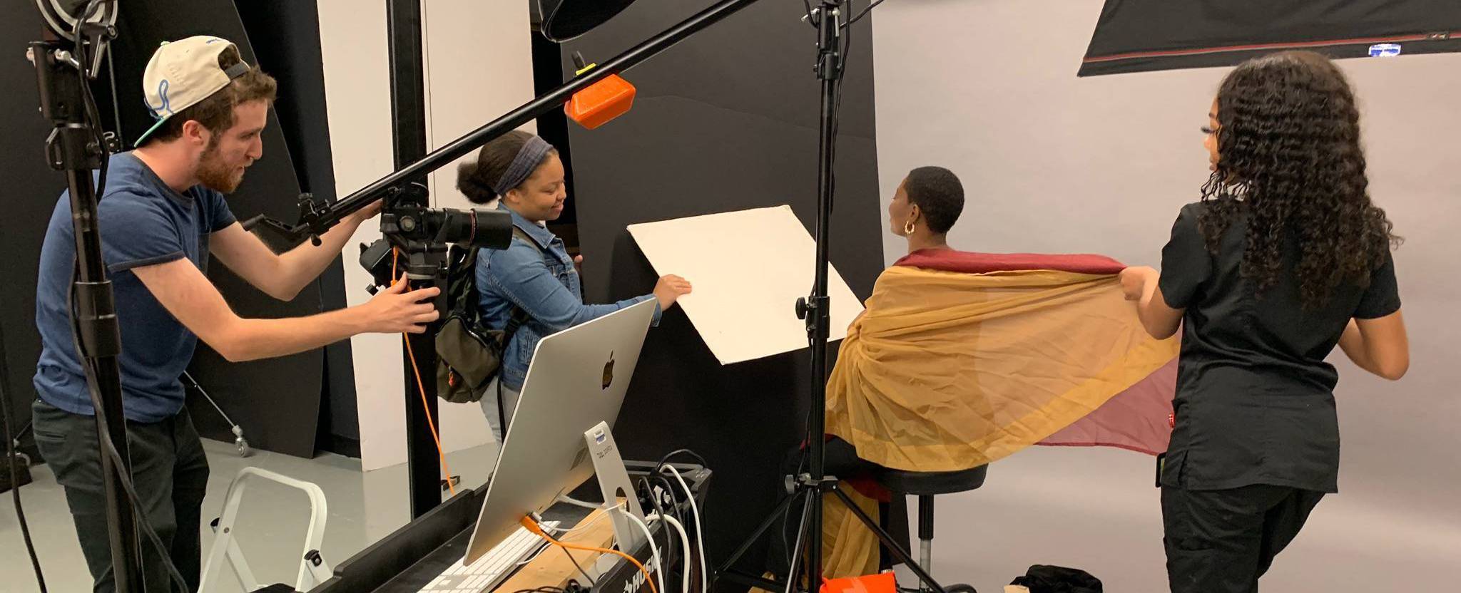 three students in photo studio with model in colored scarves