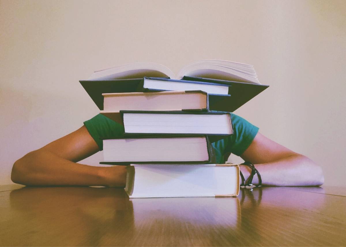 stack of books with a person behind them with their head down