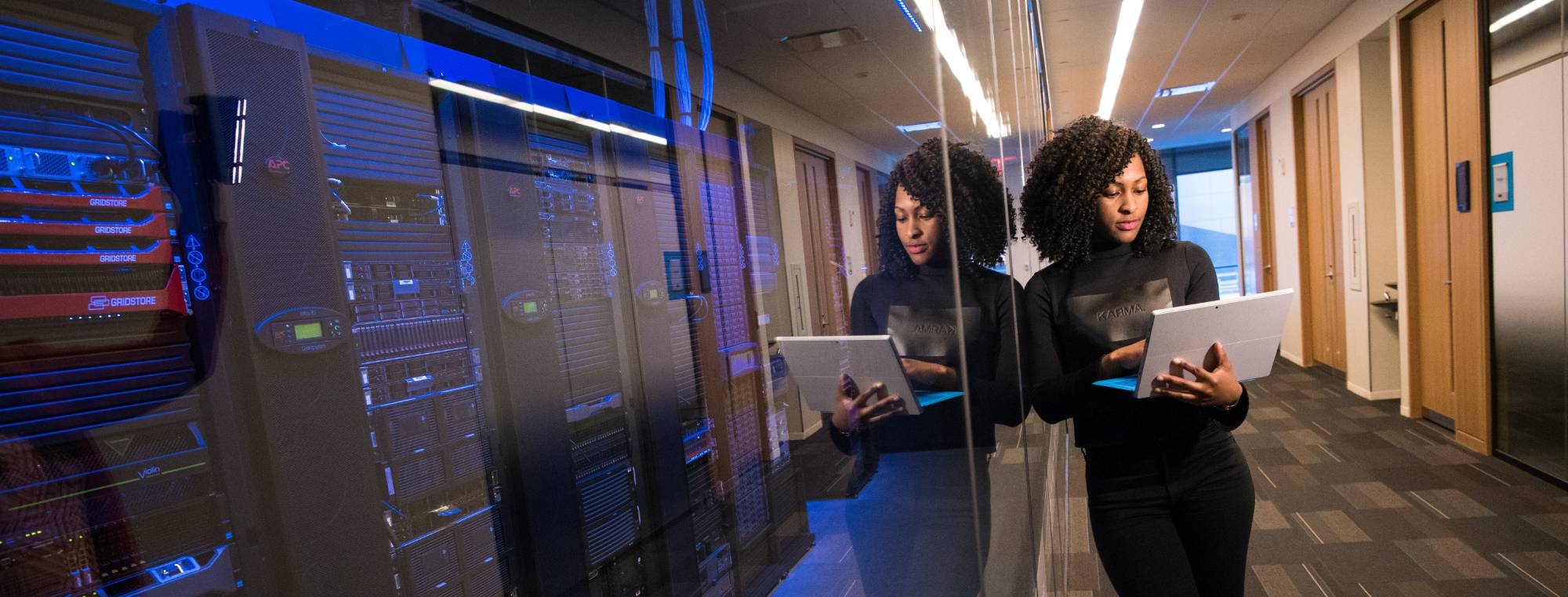 person working on a laptop in front on server room