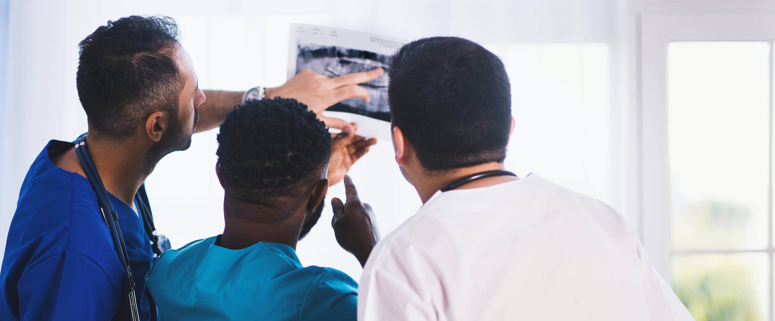 three healthcare workers looking at an x-ray