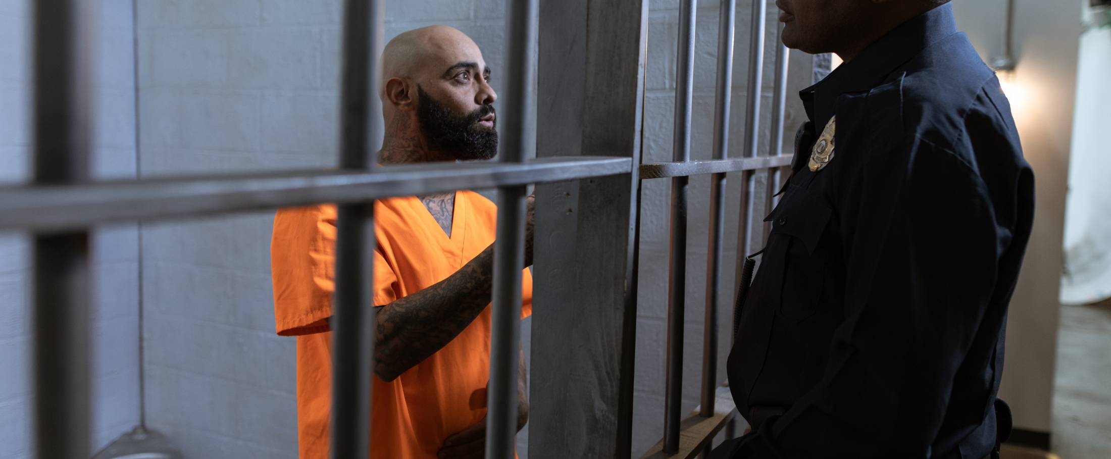 officer talking to inmate behind bars