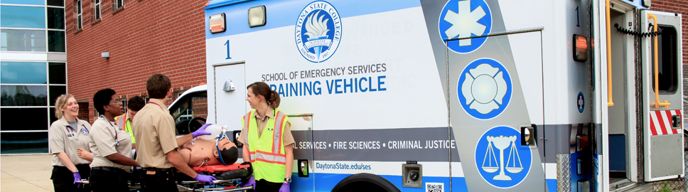 students outside school of emergency services training vehicle