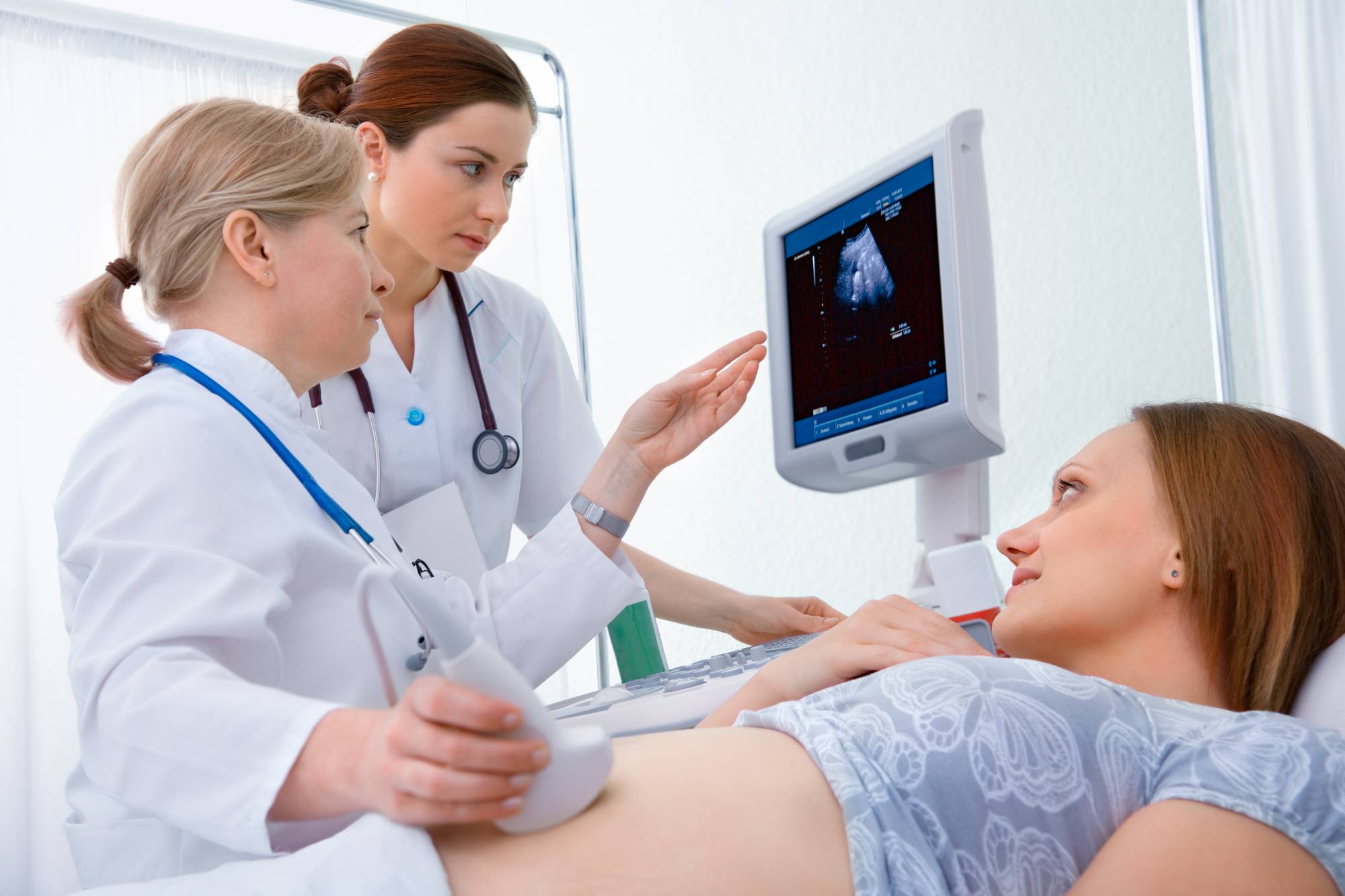 Two female sonographers checking pregnant patient