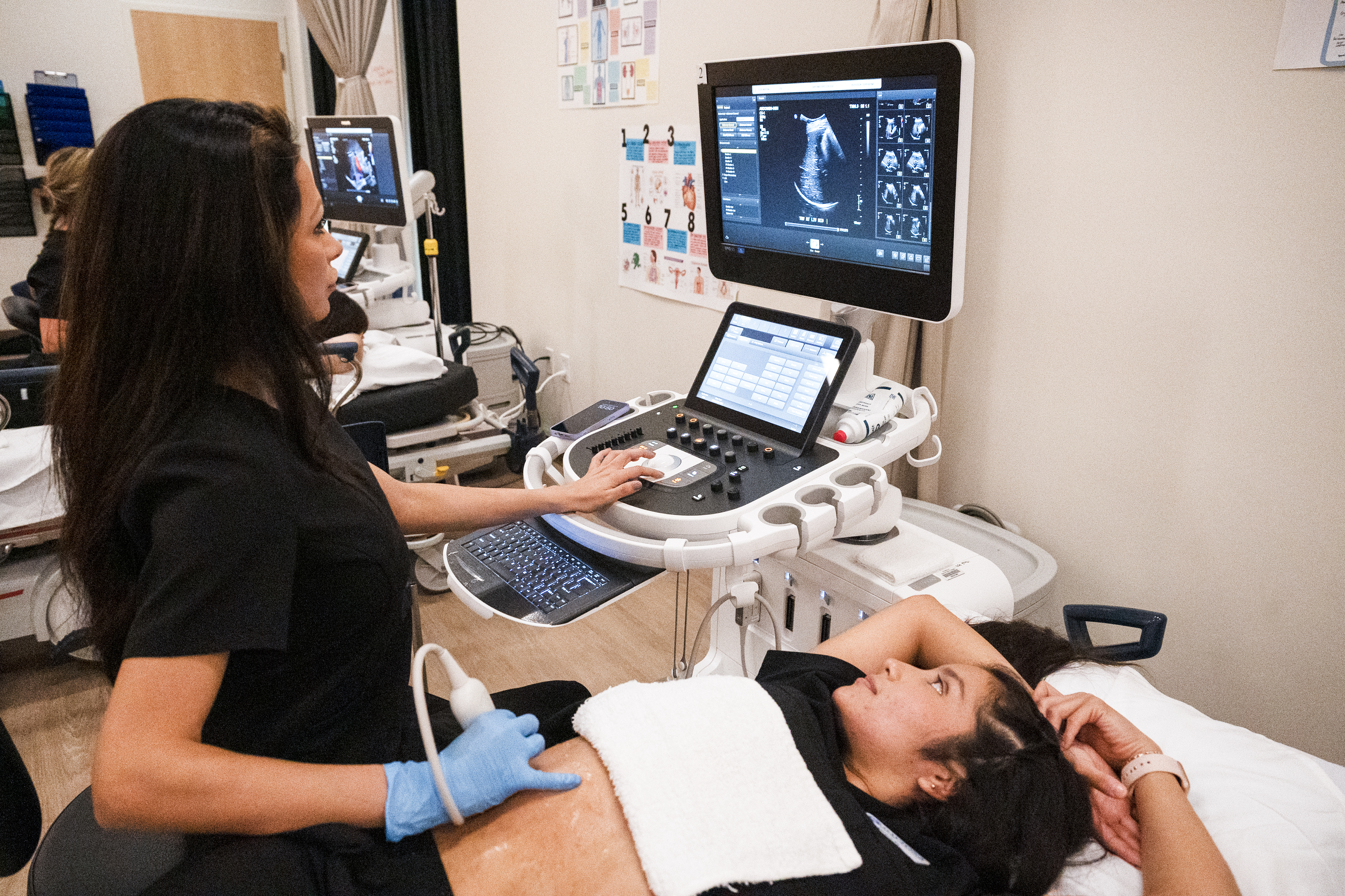 Two female sonographers checking pregnant patient