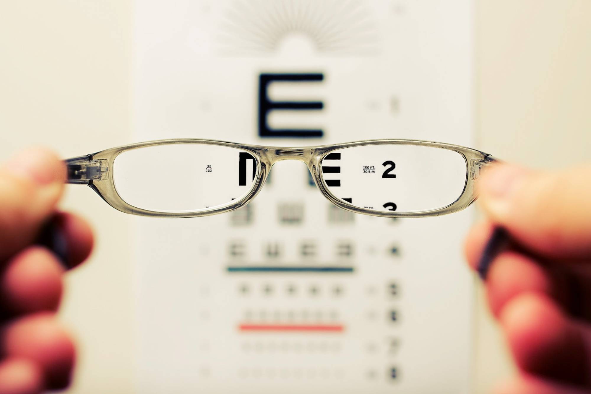 glasses held up to an eye chart
