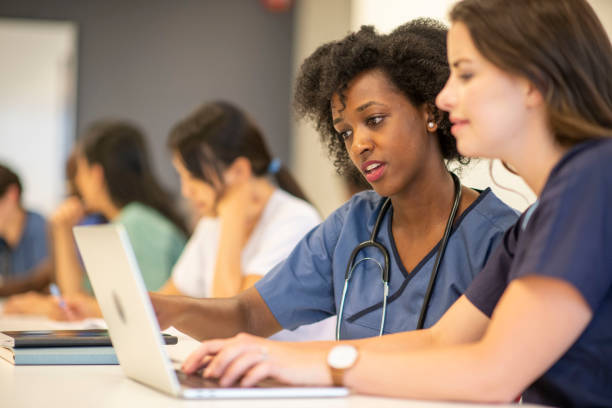 two nursing students on a laptop in a classroom