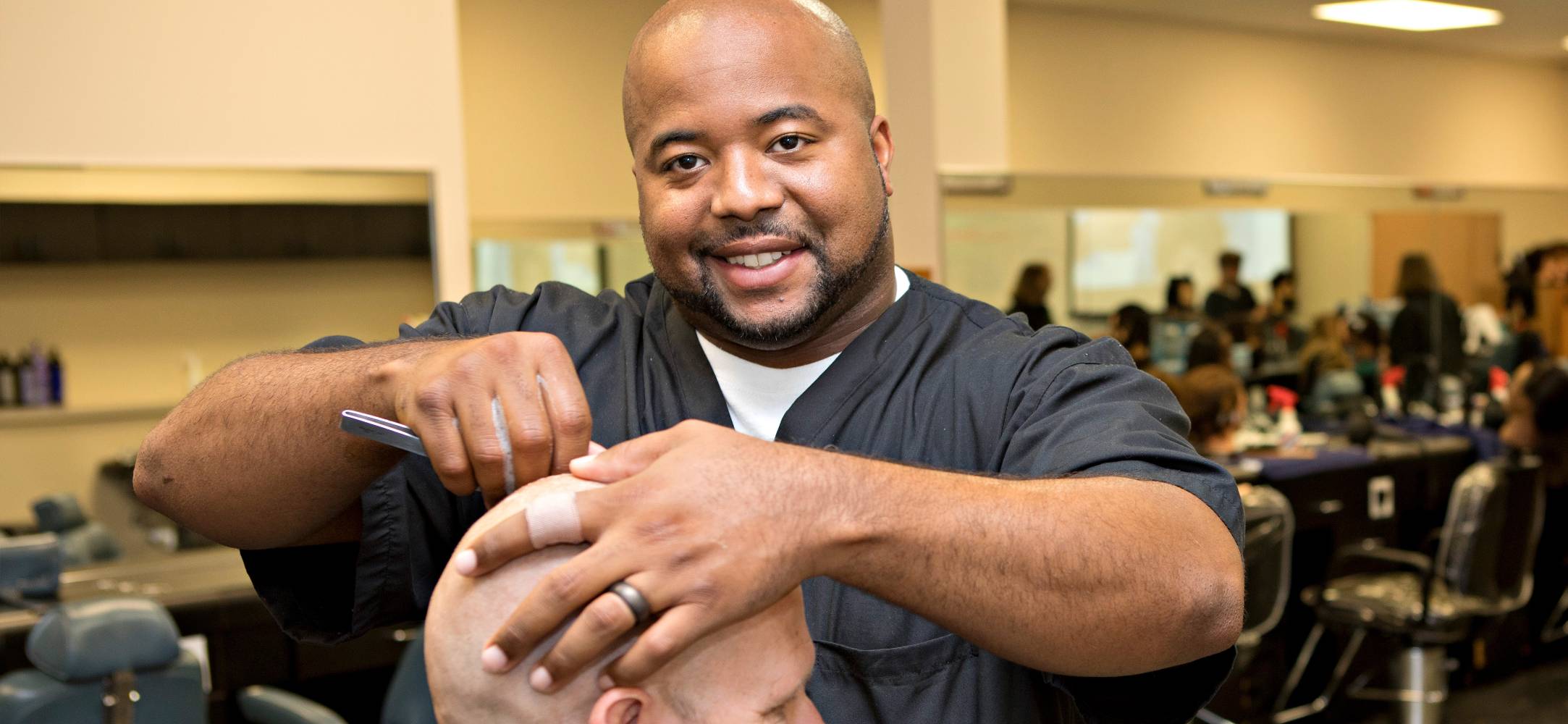 Barbering student shaving a client's head