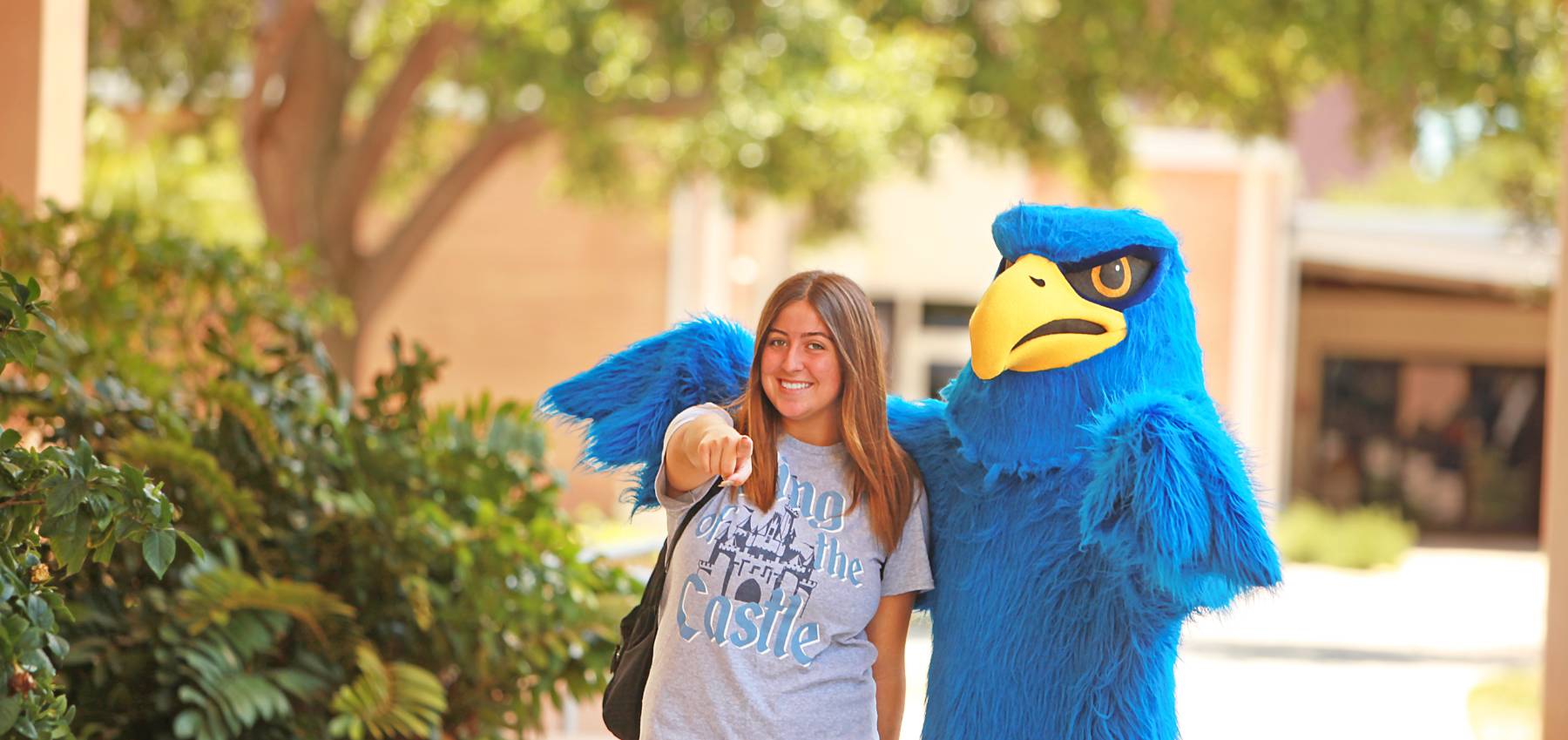 student walking with Freddie Falcon outside pointing