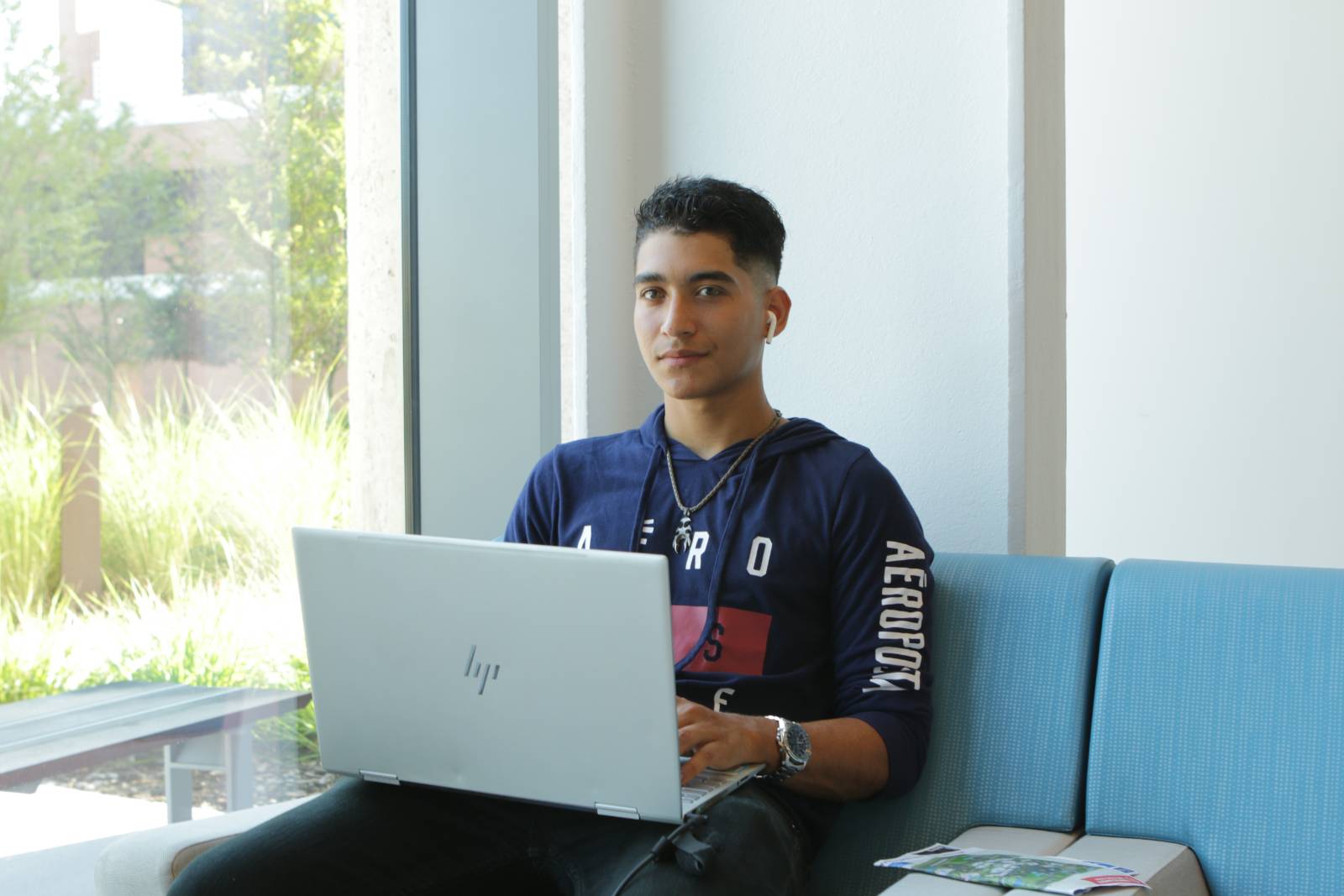 student sitting with laptop wearing ear buds