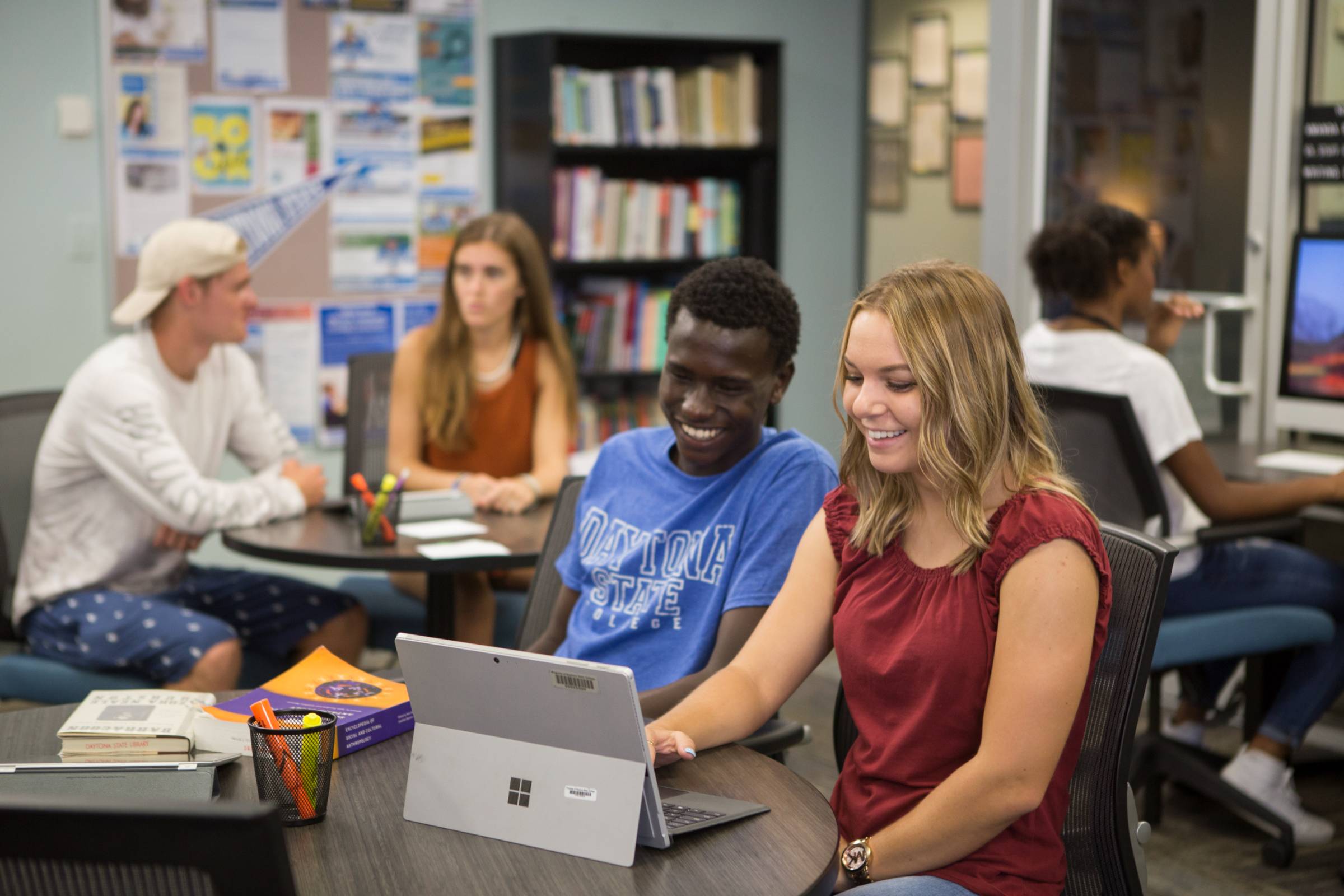 two student at a desk looking at a laptop smiling