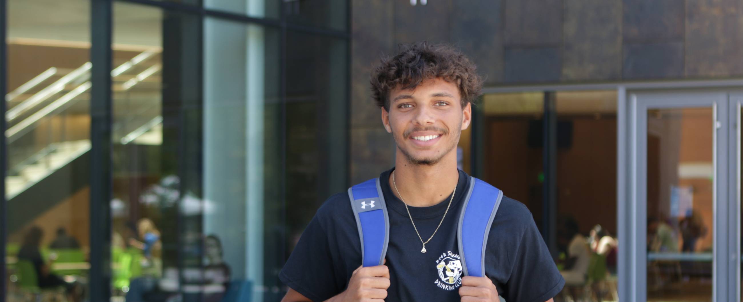 student smiling outside with blue backpack