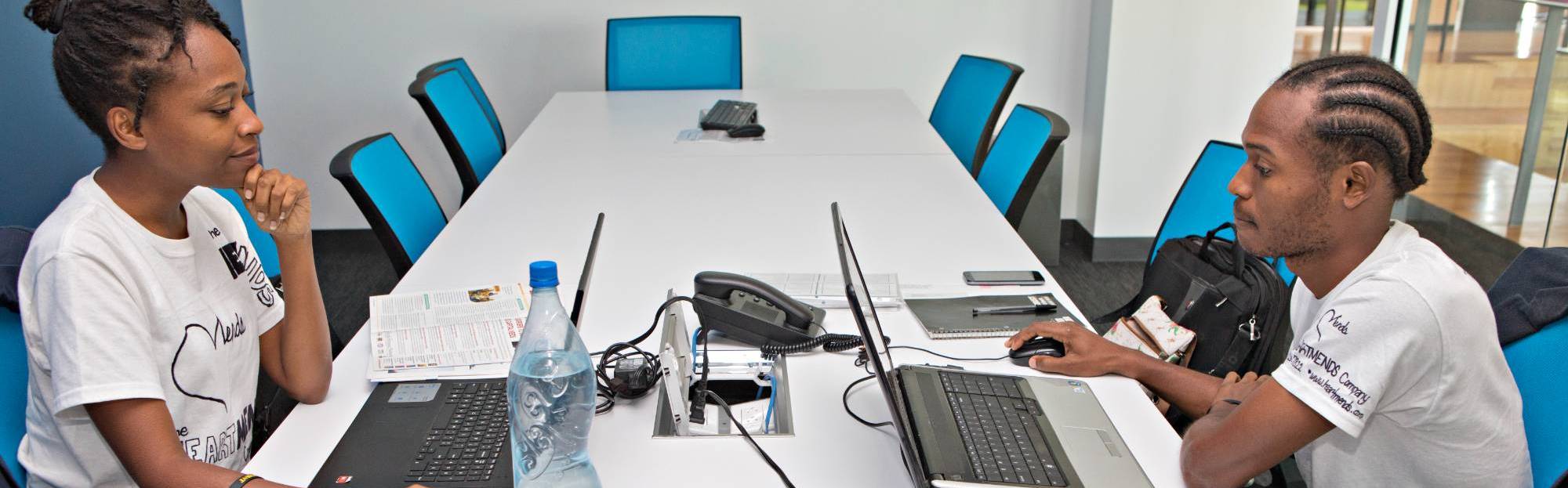 two students at a work desk on laptops