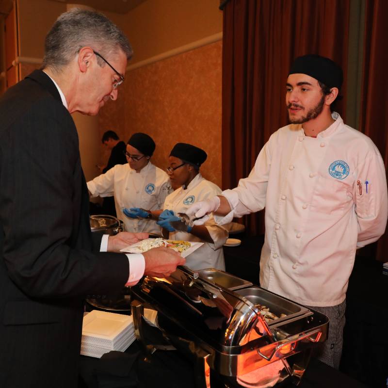 student serving guest at annual gala
