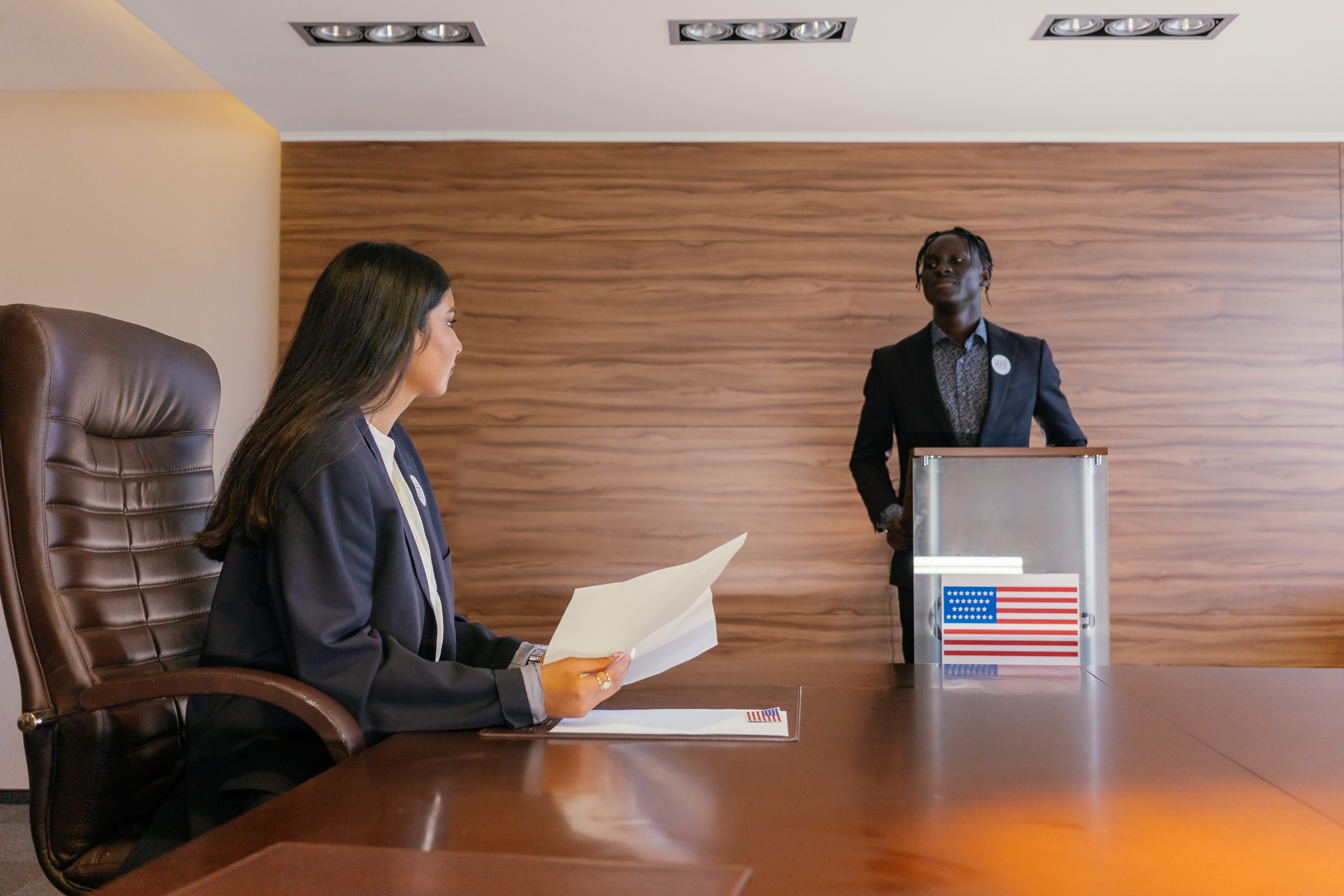 two people at conference table with a ballot box