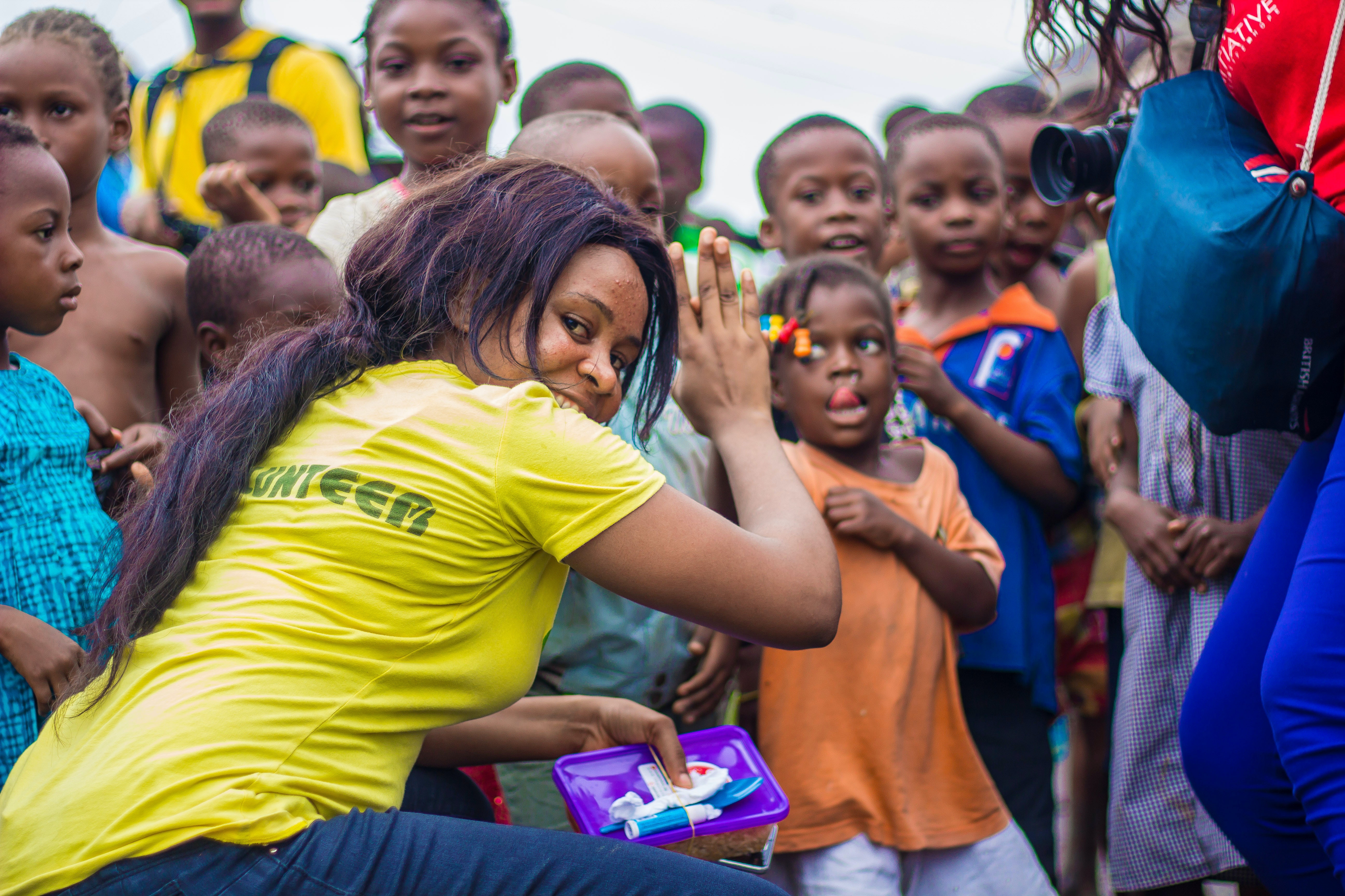 person in yellow volunteer shirt surrounded by children