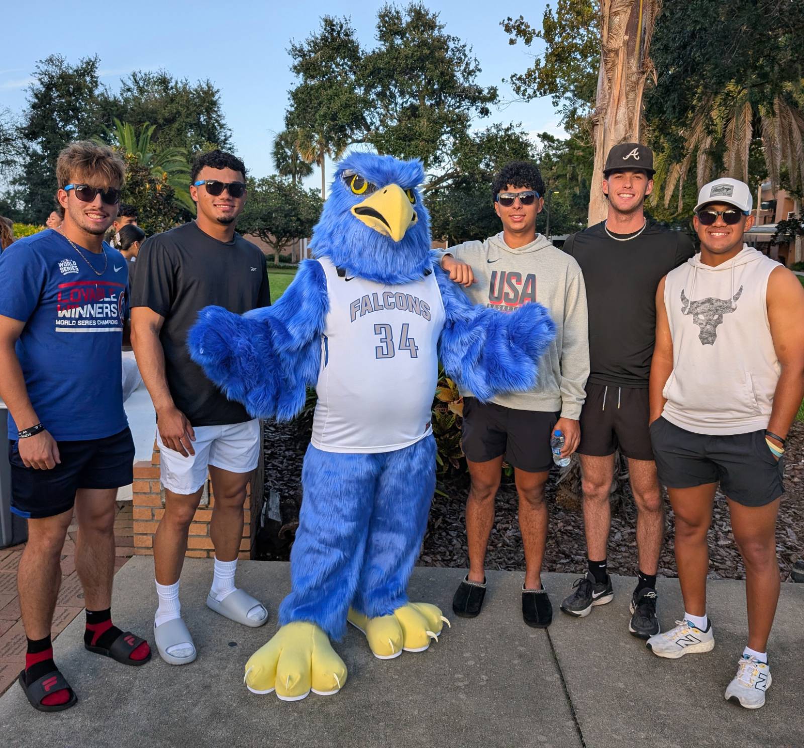 Freddie Falcon posing with students at homecoming.