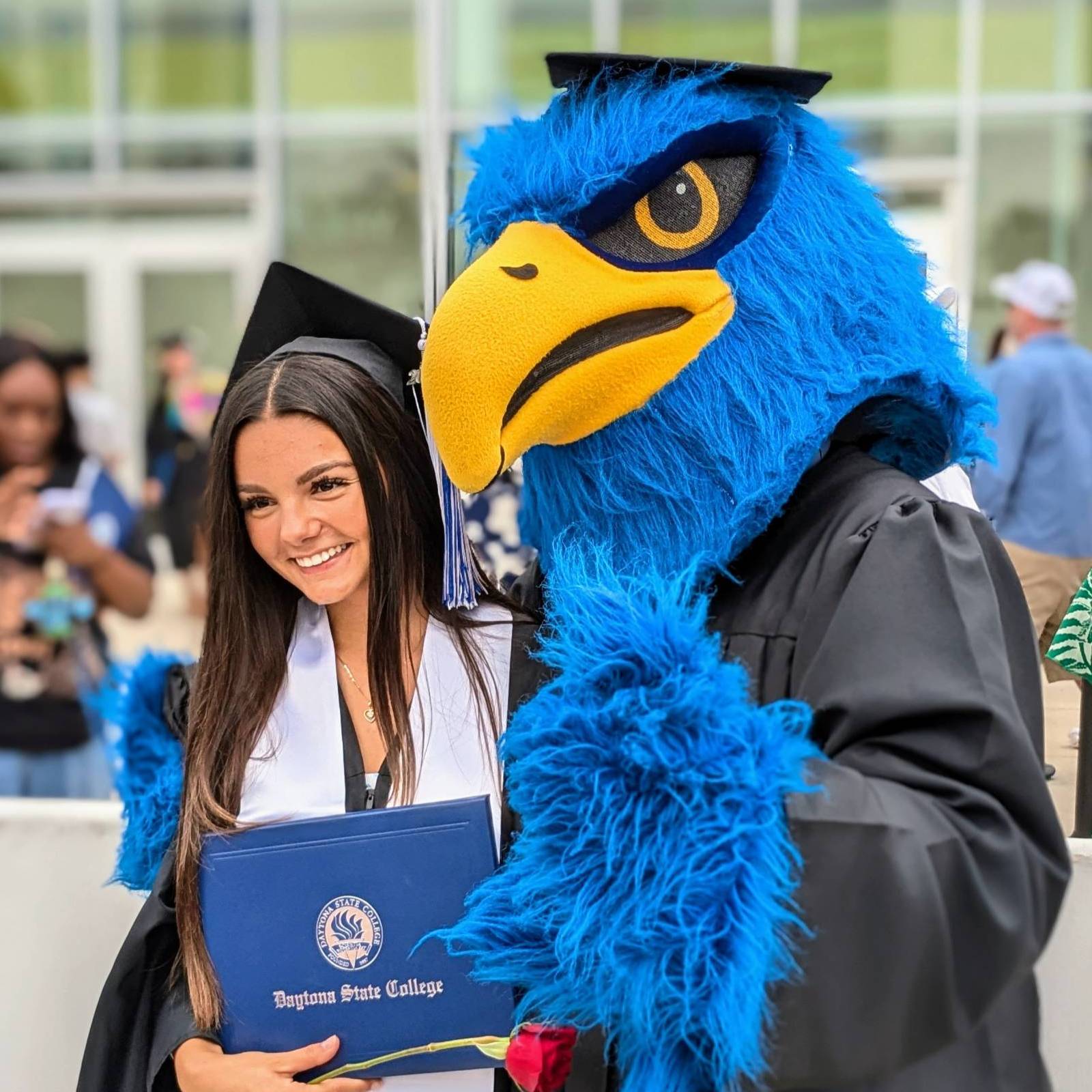 Two female students smiling at the camera standing in the courtyard in front of the student center