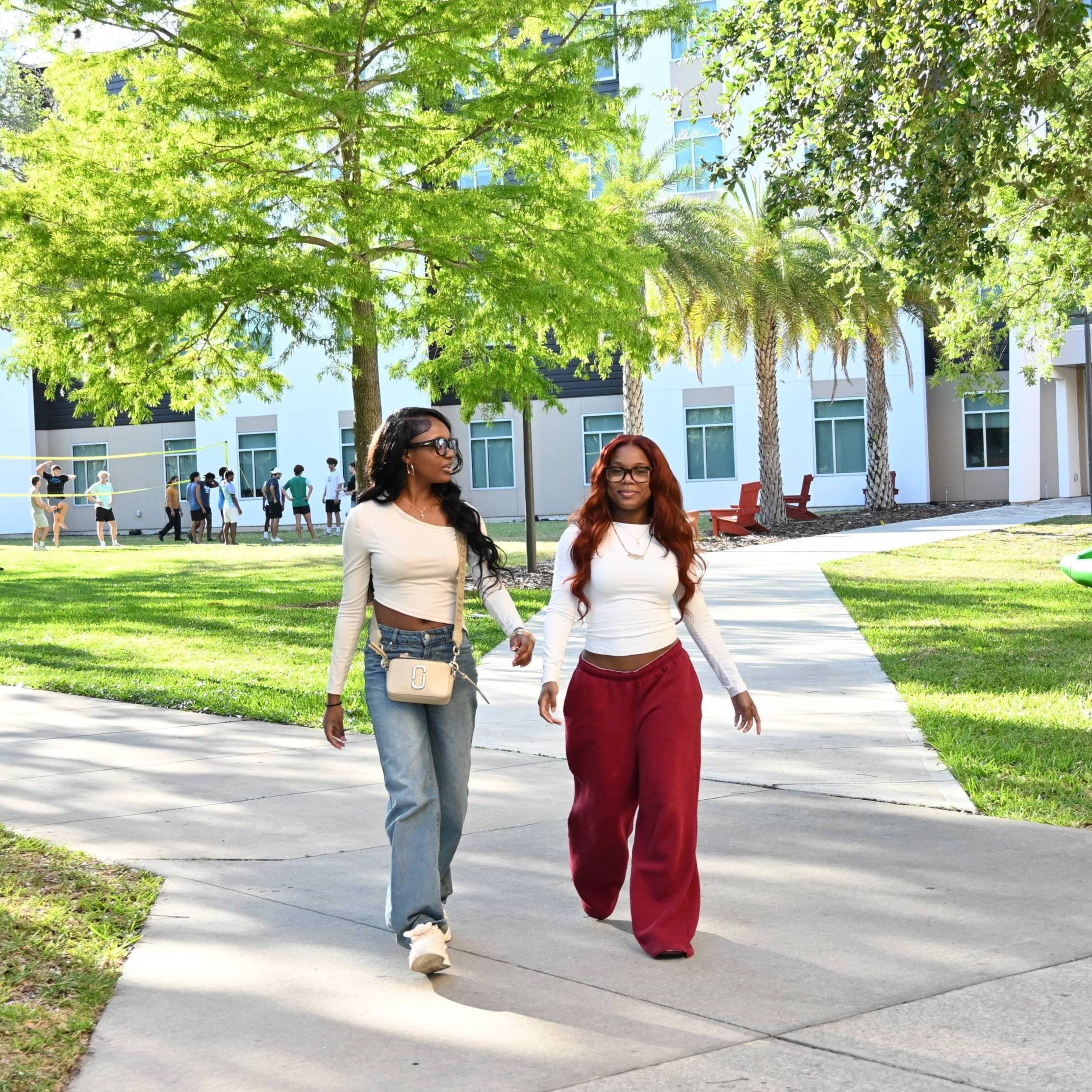 Two female students smiling at the camera standing in the courtyard in front of the student center