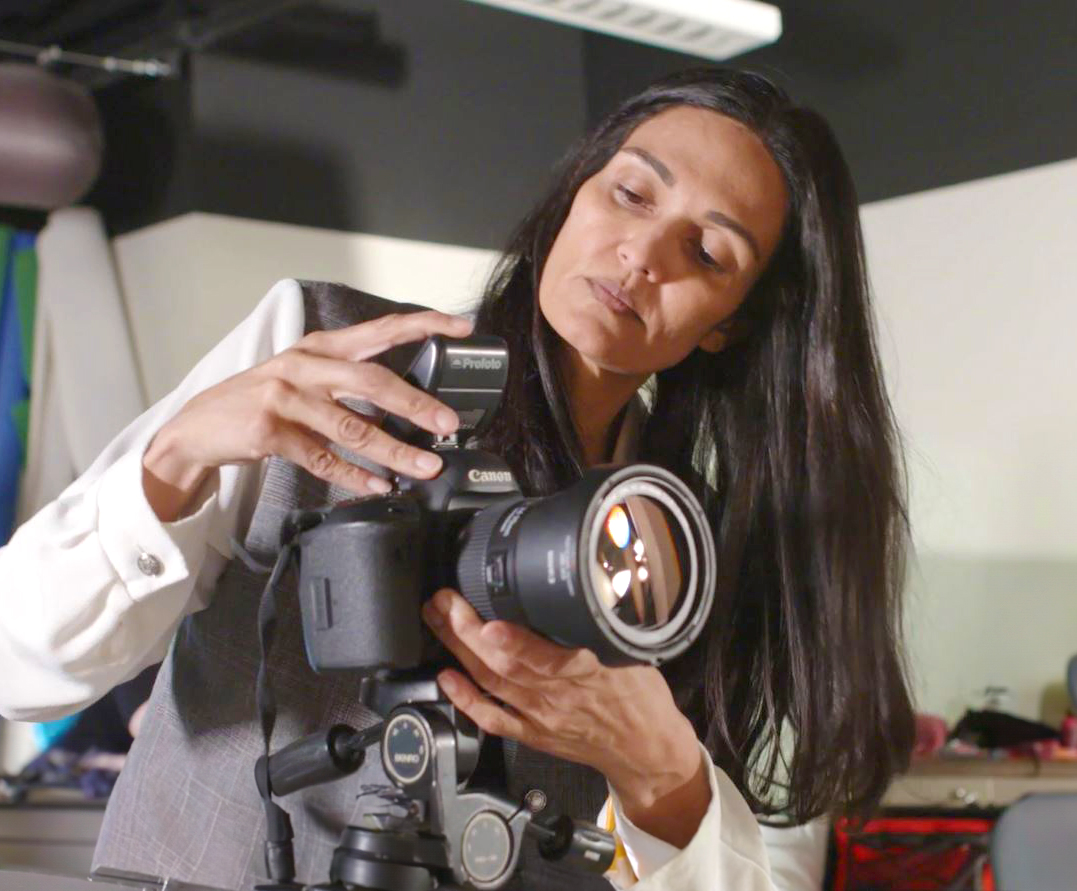 A photography student adjusting her camera in the studio. 