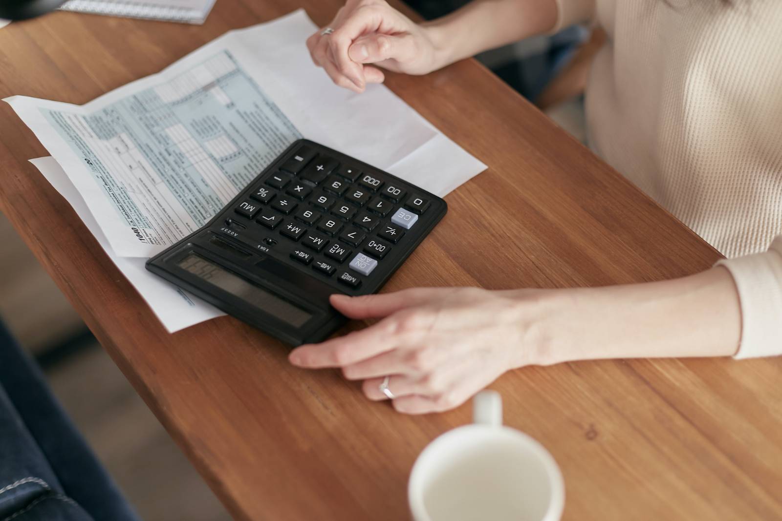 person holding tax documents and a calculator