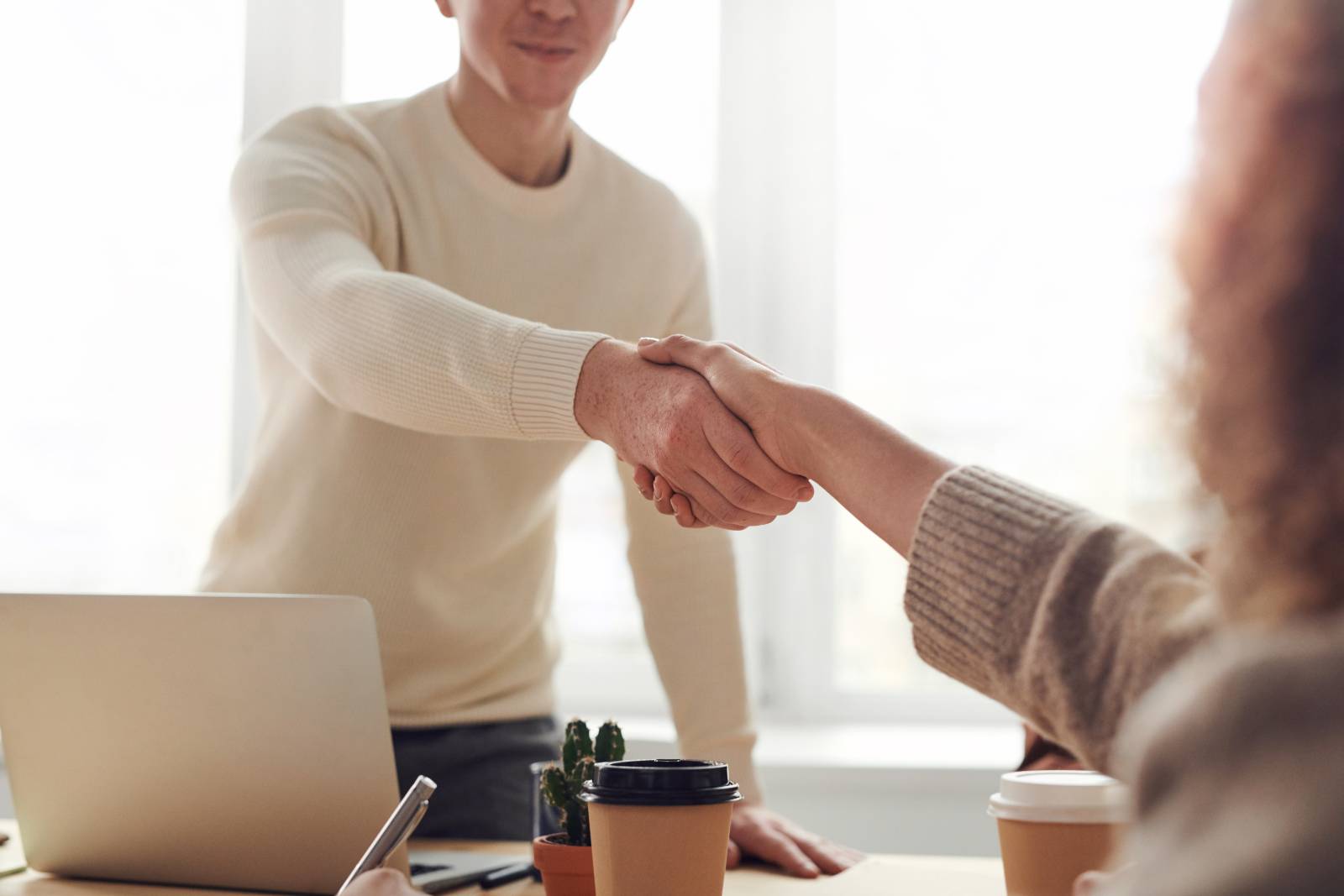 people shaking hands over a laptop