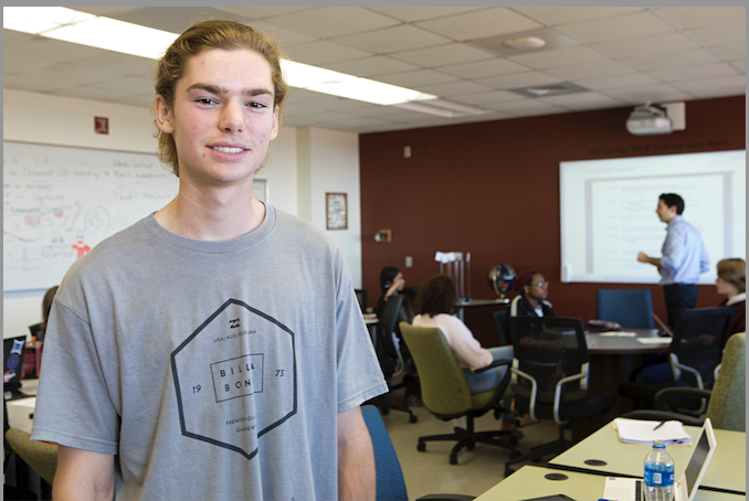 student in gray shirt standing in classroom