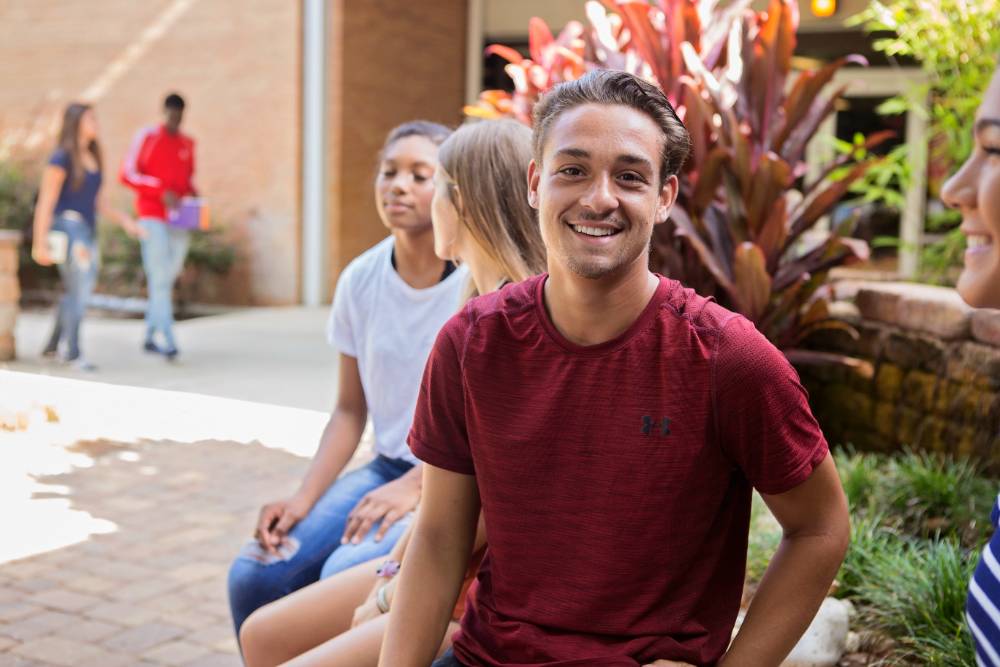 Student sitting with friends in an on-campus garden. 