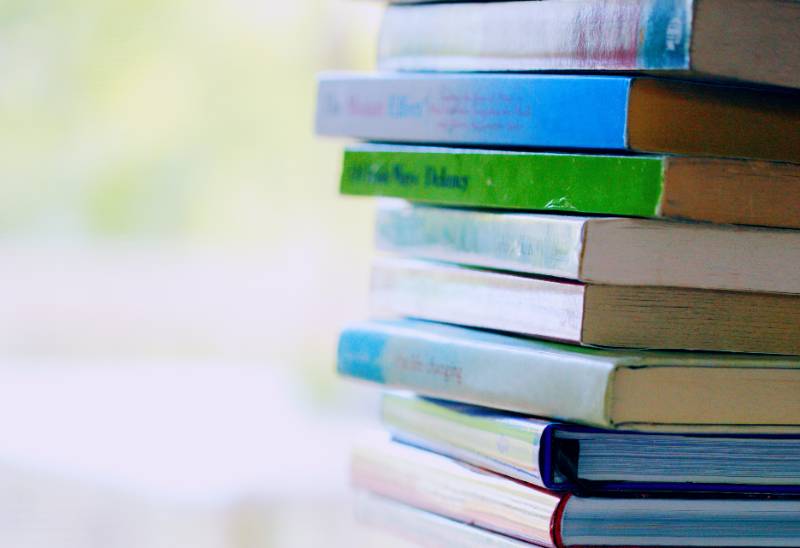 stack of books on a table in a bright room