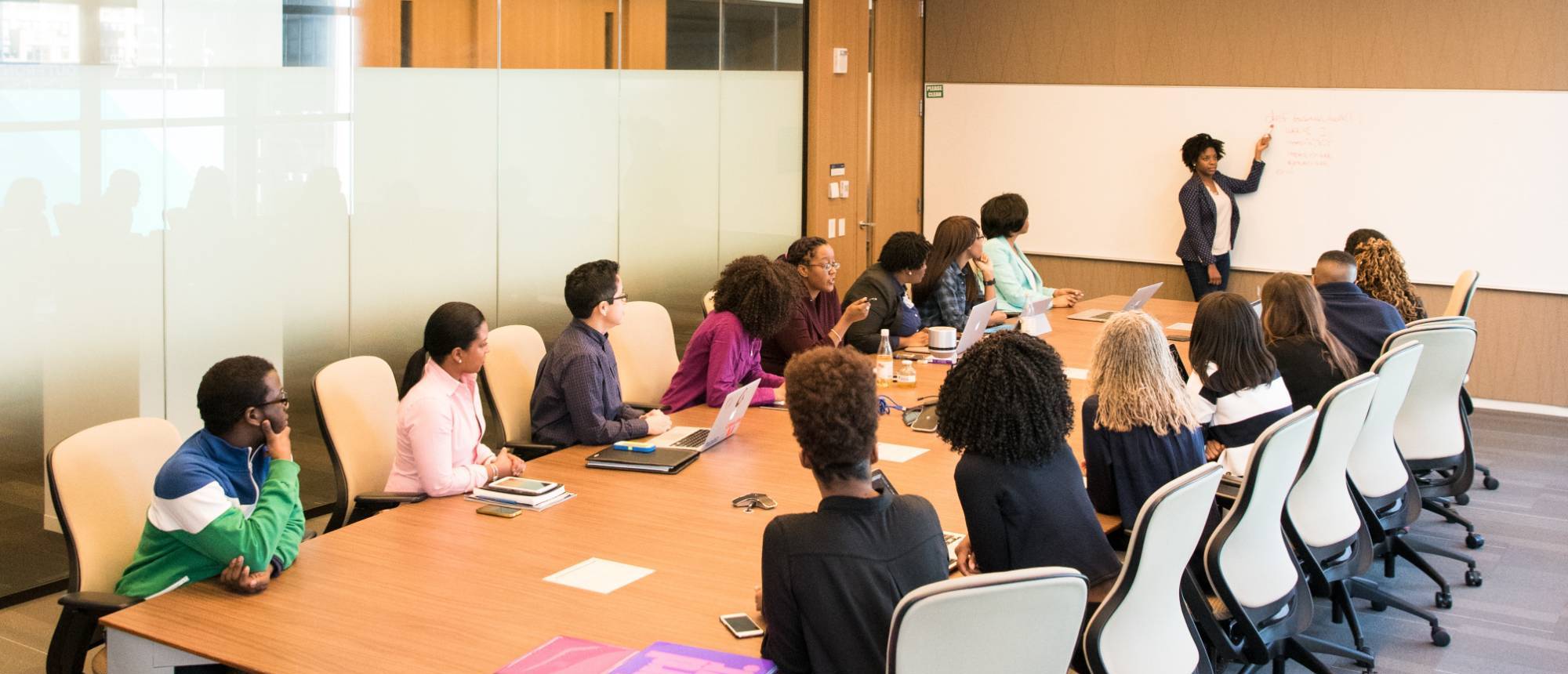 employees in a conference room with a person presenting at a white board