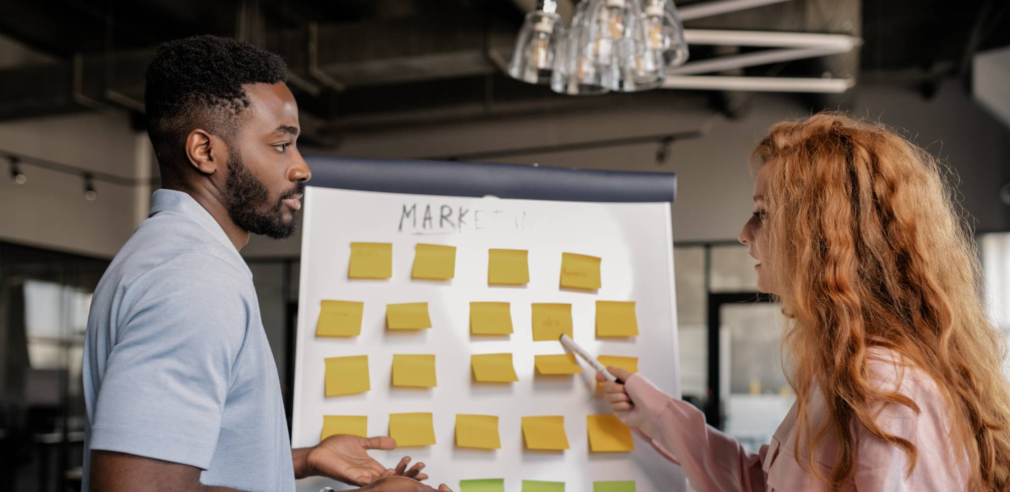 two people working on marketing strategy at a whiteboard 