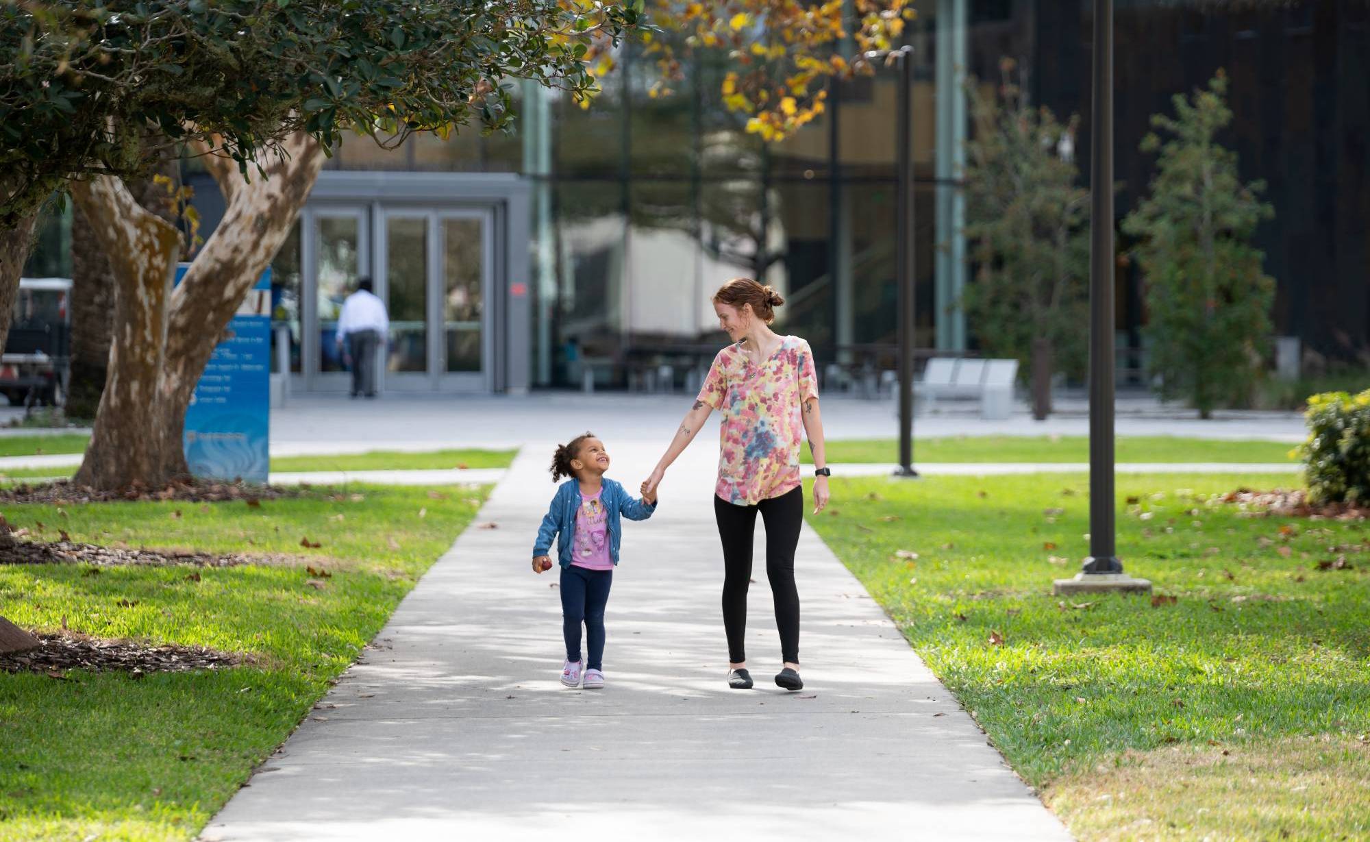A Falcon HOPE student parent and her child enjoying walking on campus.