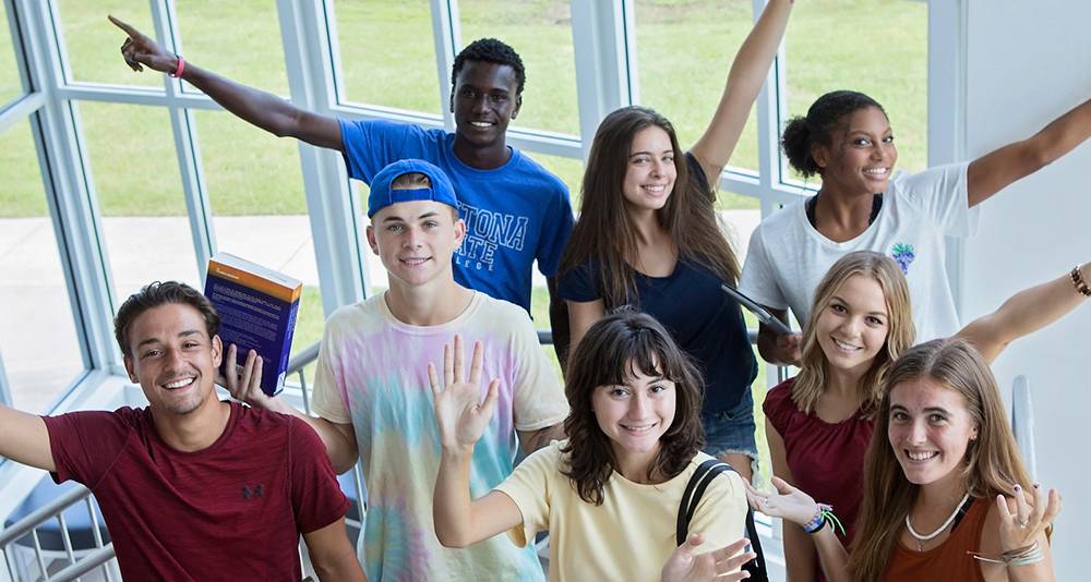 students standing with arms raised on staircase