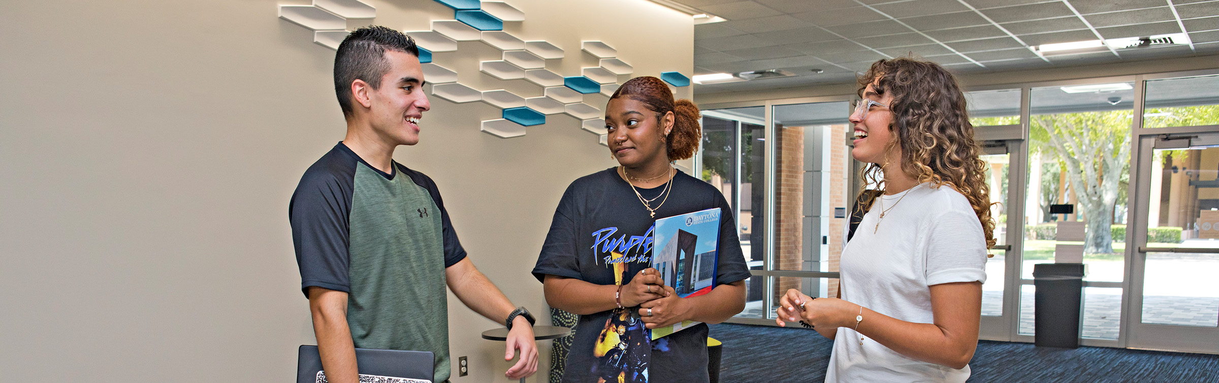 3 students talking in hallway. 