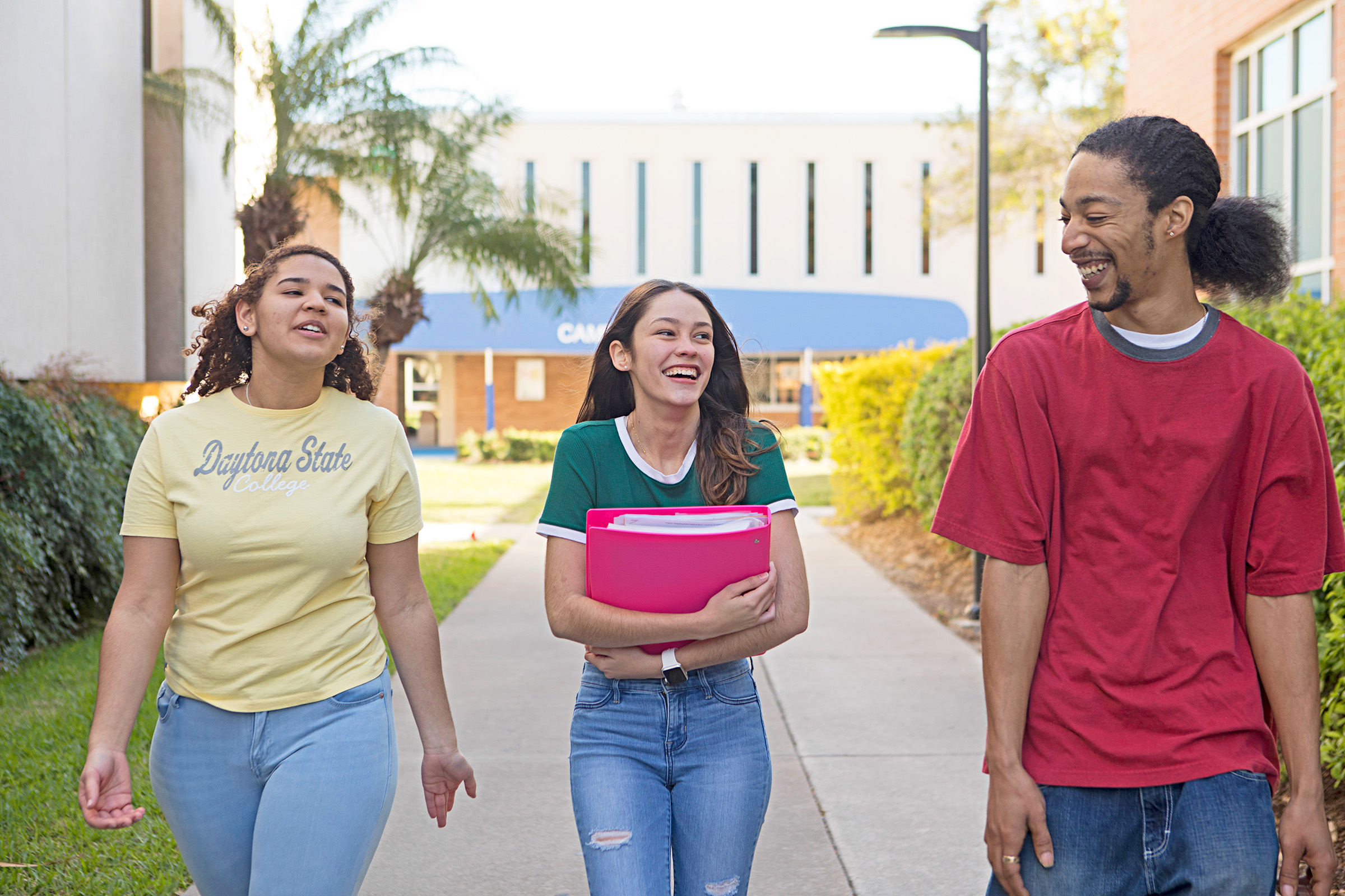 2 females and male student walking on campus