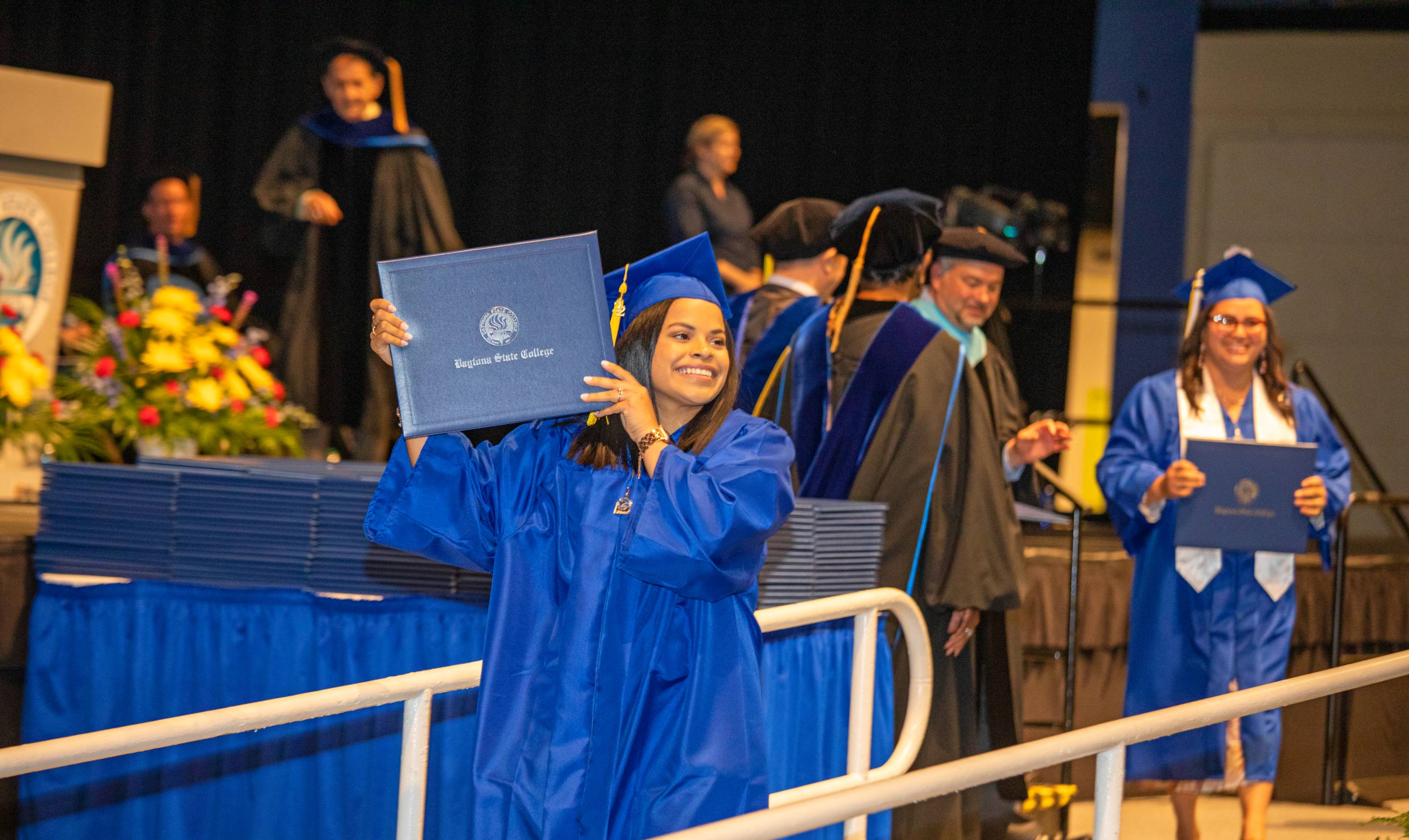 Happy and proud students walking across the stage at graduation.